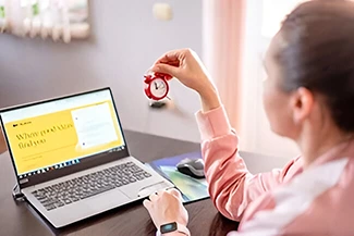 A woman sits at a desk with a laptop and timer, exemplifying her skill in time management and organization.
